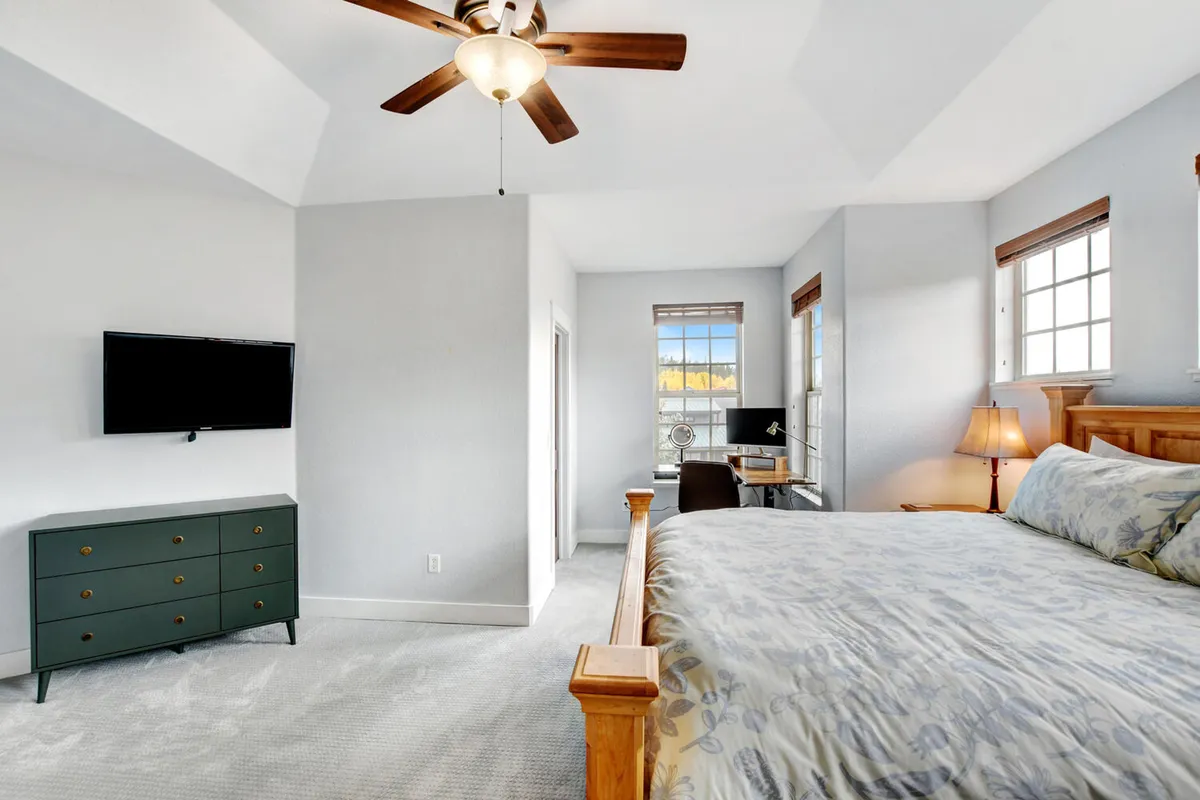 The image captures a tranquil bedroom with a bed, dresser, and a desk by the window. Ample natural light streams in, revealing sunrise views and providing a cozy reading corner and a productive workspace.