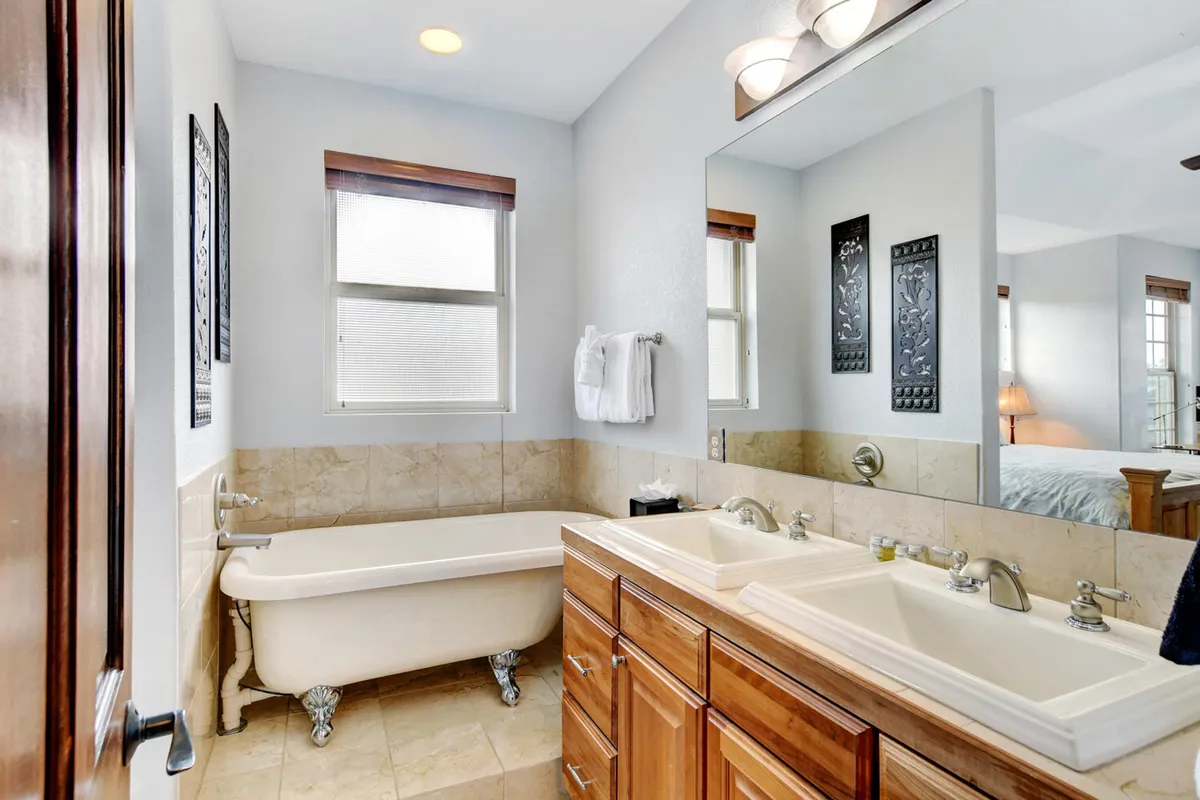 An elegant bathroom with a freestanding bathtub, double sink vanity, and large mirror. The space is bright and tranquil, designed for relaxation and self-care.