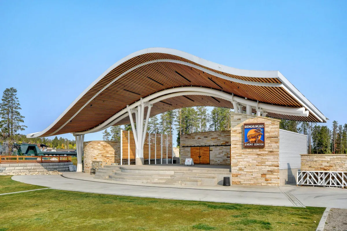 The Hideaway Park amphitheater, with its distinctive curved roof, stone walls, and stage area, set outdoors. The venue hints at live performances, concerts, and community events that define the downtown Winter Park experience.