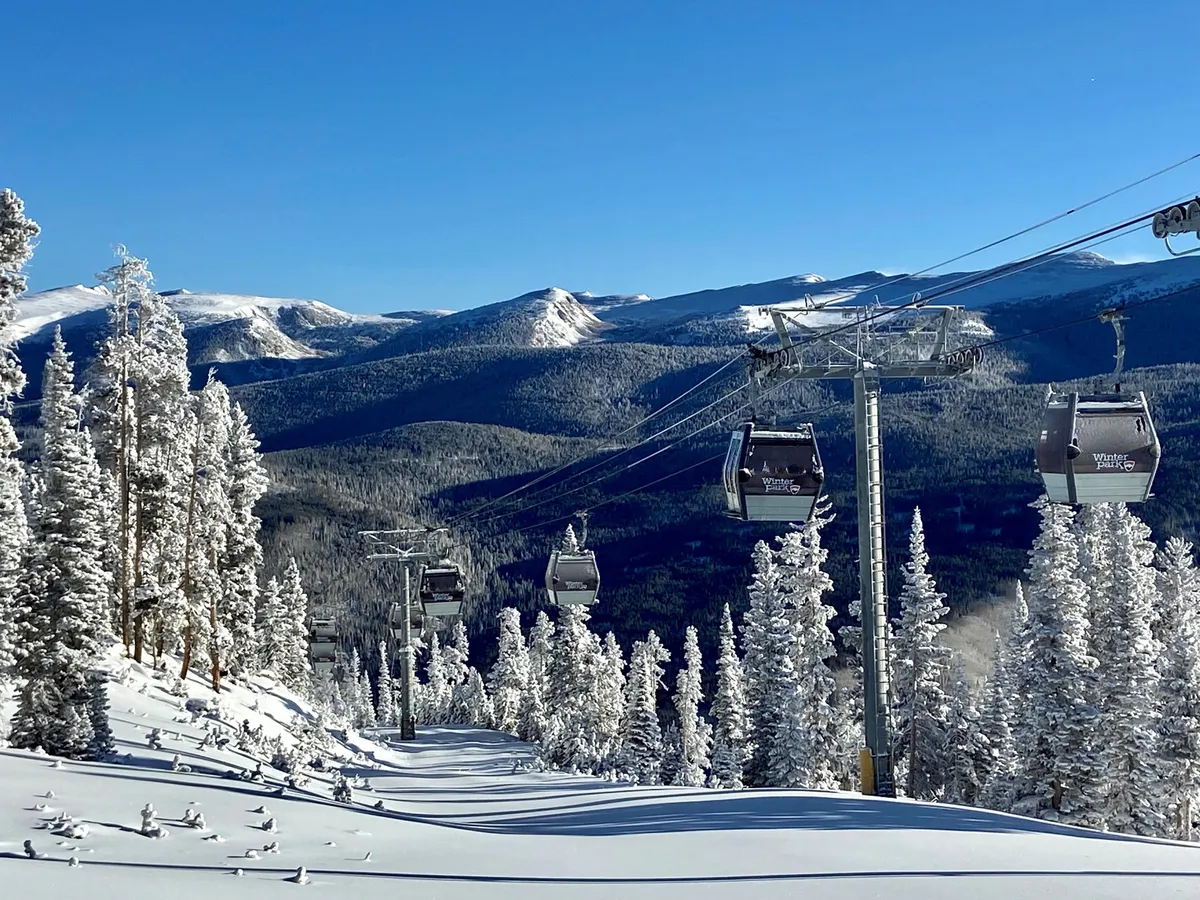 A scenic exterior shot with ski gondolas gliding above snow-covered trees and a dramatic mountain range in the background. The landscape is peaceful yet adventurous, hinting at the excitement awaiting guests as they set out for winter sports.
