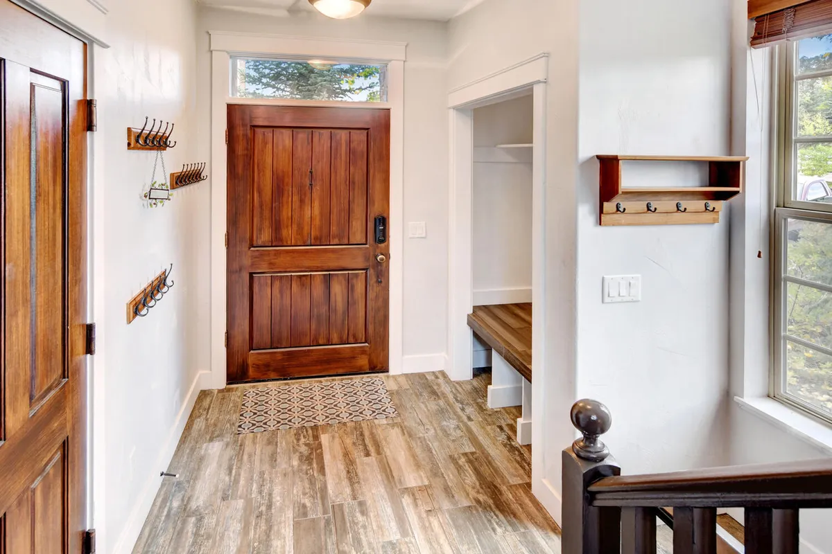 This image showcases the villa's welcoming entryway, featuring the front door, a wooden bench, and coat hooks. The area rug and natural lighting create an inviting first impression, suggesting a seamless transition between indoor comfort and the outdoors.